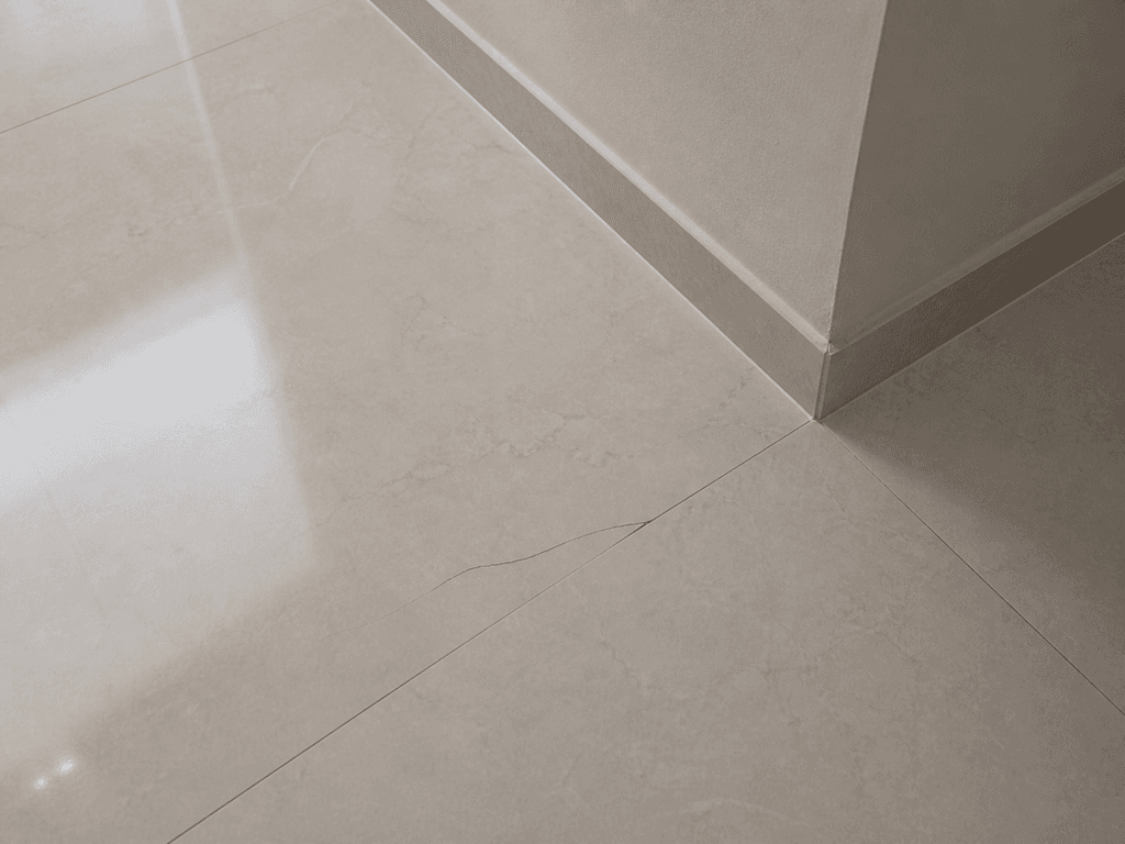 Trinca em piso porcelanato próximo ao canto da parede